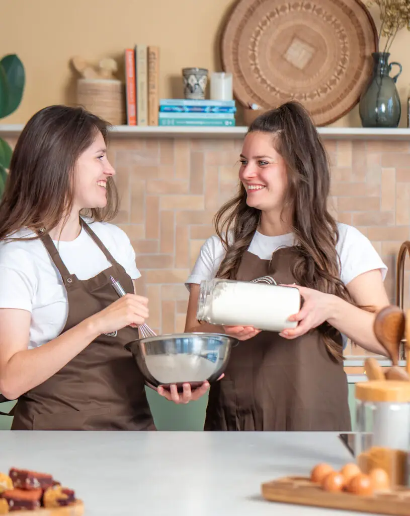 De zussen achter Smulpost in de keuken, met een kom en een pot bloem